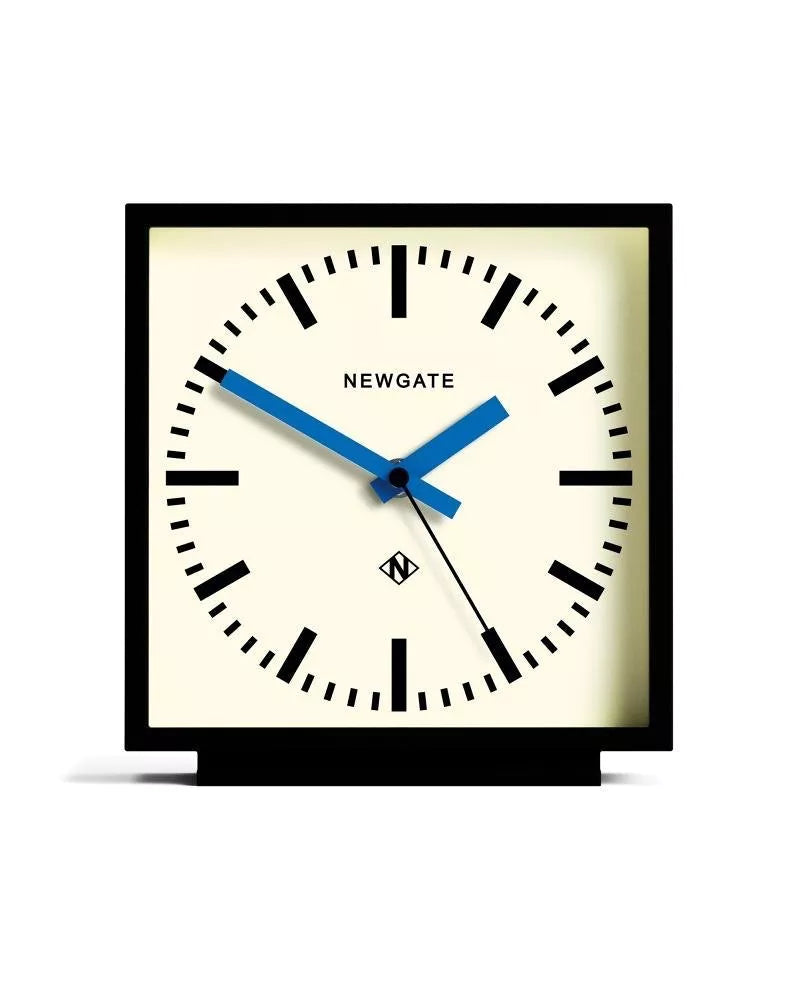 Horloge carré à poser de la marque New Gate, design des années 1900 à 2000, avec un boîtier noir mat et un cadran couleur crème et aiguilles bleues.