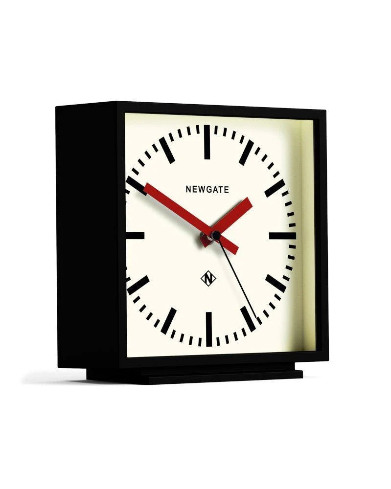 Horloge carré à poser de la marque New Gate, design des années 1900 à 2000, avec un boîtier noir mat et un cadran couleur crème et aiguilles rouges.