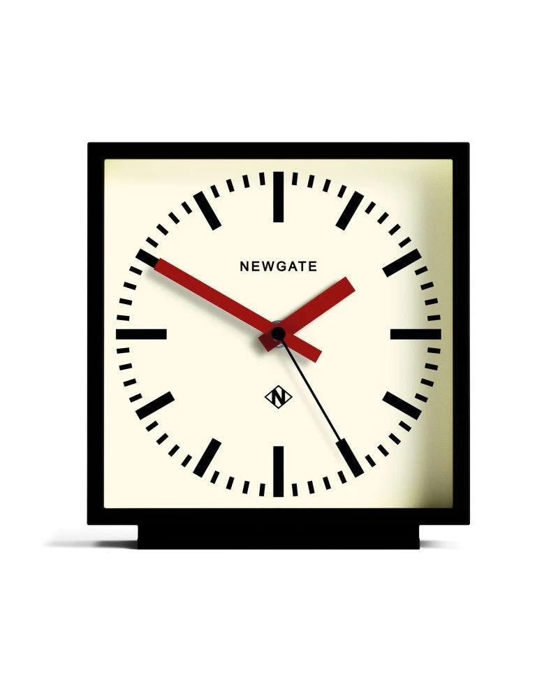 Horloge carré à poser de la marque New Gate, design des années 1900 à 2000, avec un boîtier noir mat et un cadran couleur crème et aiguilles rouges.